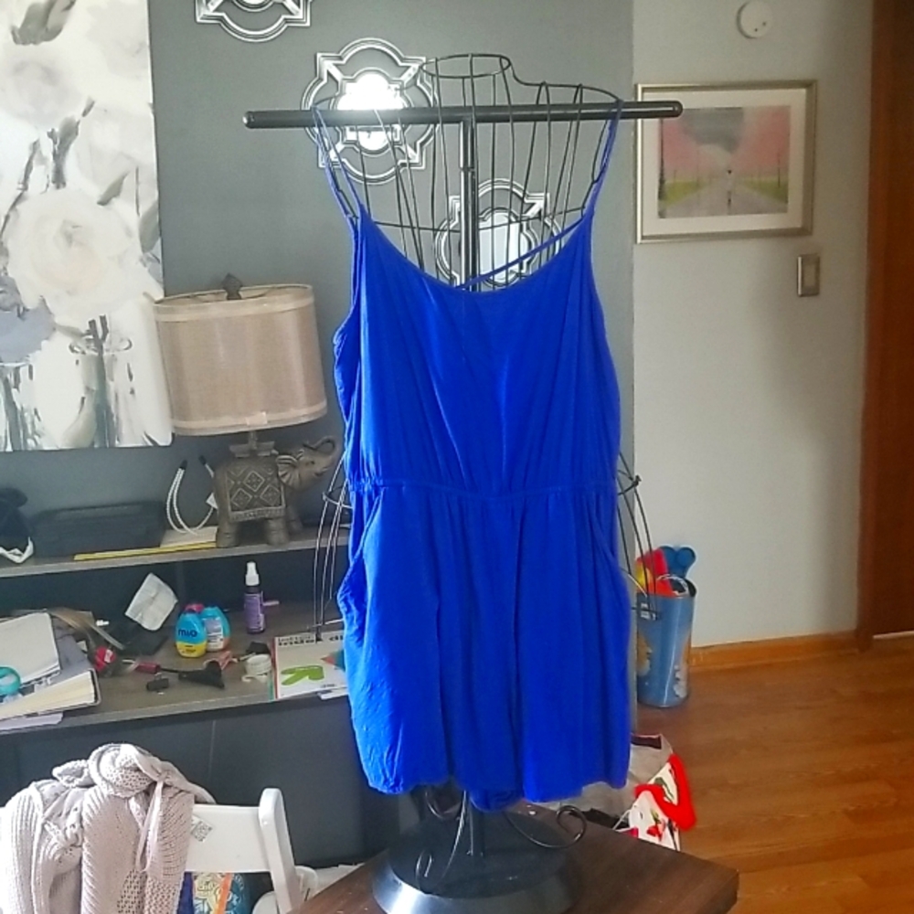 Blue short romper with adjustable straps and two pockets crisscross is in the ba